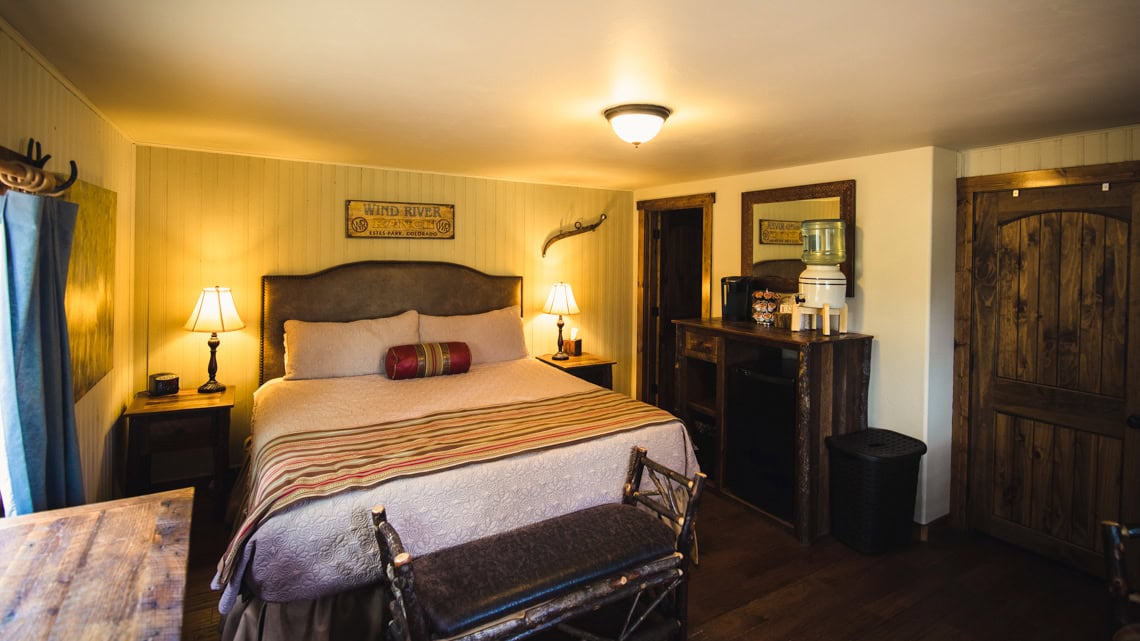 A hotel room with a king-sized bed, two nightstands, and a window