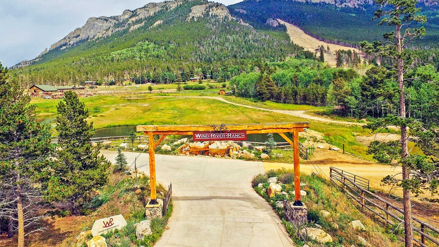 A pathway leads to an entrance archway with a mountain view in the background.