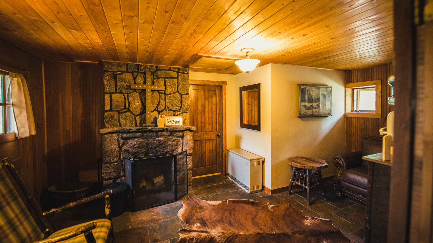 A cozy lobby with a stone fireplace, wood paneling, and comfortable seating.