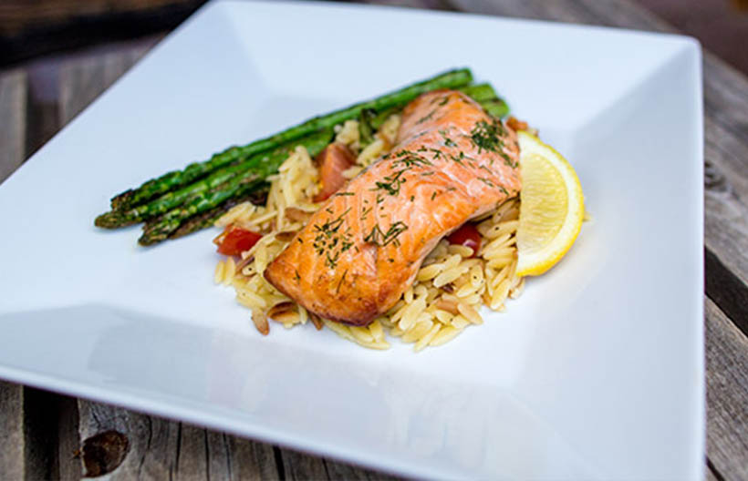 A plated meal of salmon, asparagus, and rice on a white plate.