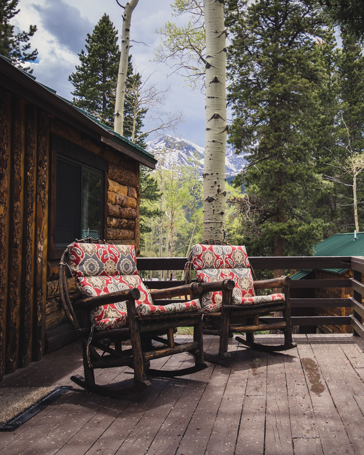 Two rocking chairs on a wooden deck with a mountain view